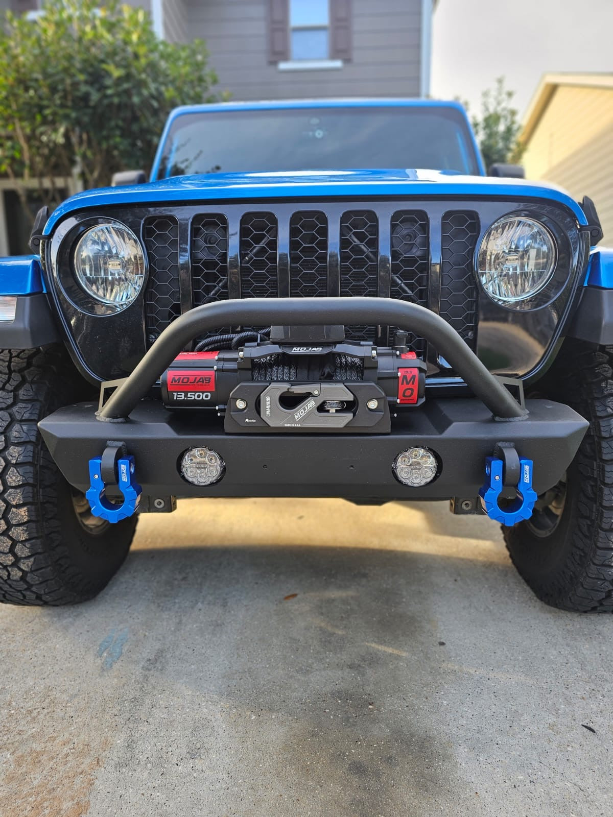 13500 Electric Winch on a blue Jeep with a black bumper and blue recovery hooks on a driveway.