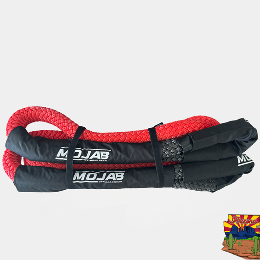 A coiled red kinetic rope designed for heavy-duty towing, displayed alongside its black durable canvas storage bag, with the brand MOJAB visible on the rope and bag.